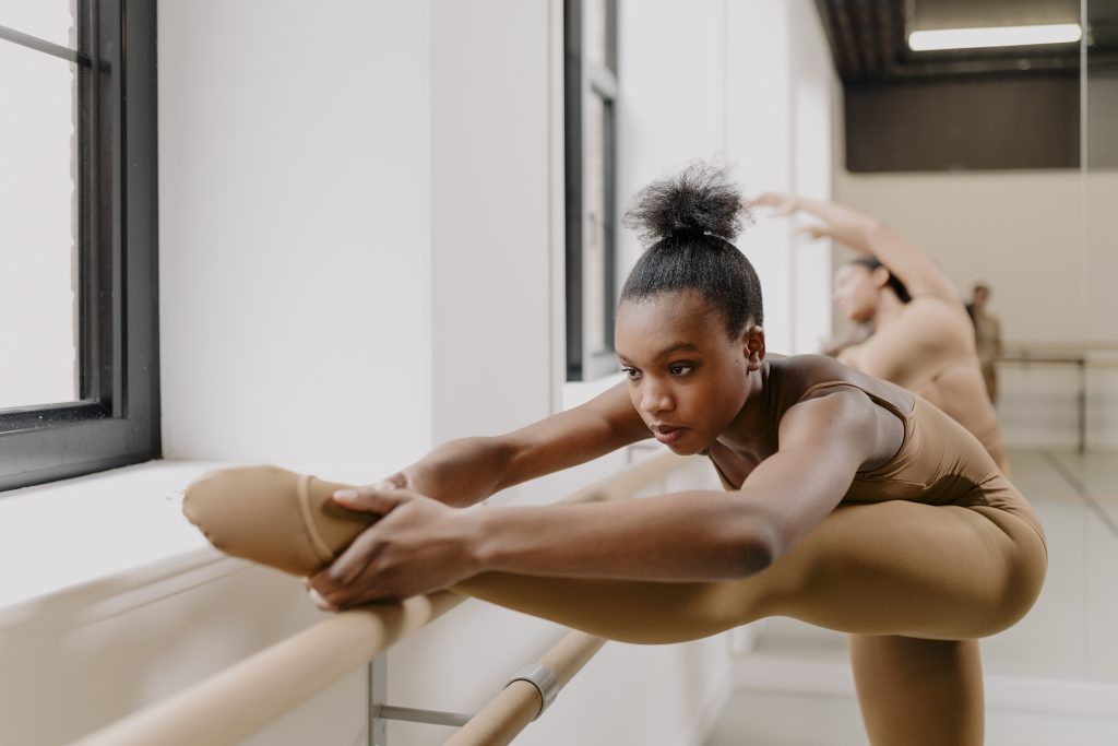 A female dancer stretching on the Ballet barre wearing matching skin tone Shades Dancewear