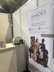 This picture shows the IDS stand at Perform Festival, Dublin. There's a large Shades Dancewear banner that reads "embrace your ethnicity, retain your identity."