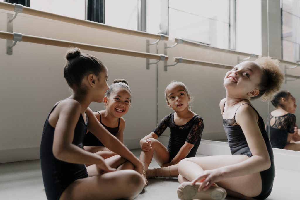 A group of children sat laughing in a dance studio