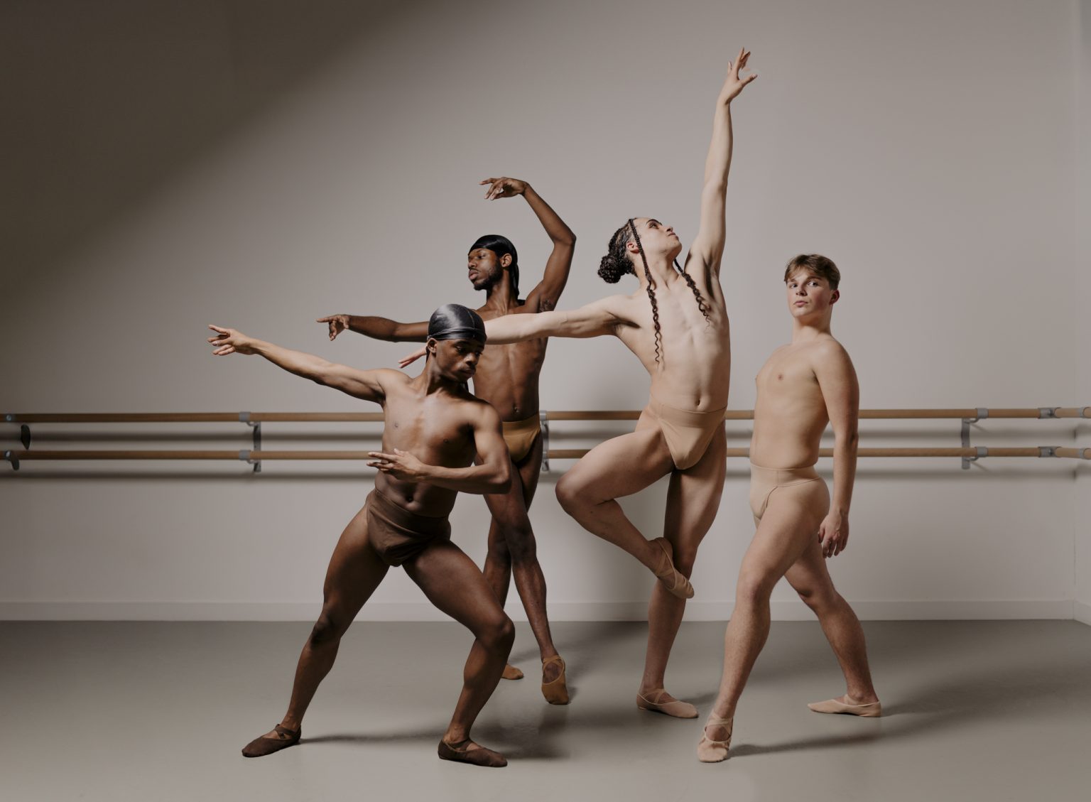 Four male presenting dancers of four different skin tones posing in their matching skin tone Shades Dancewear Ballet Dance Support Belts