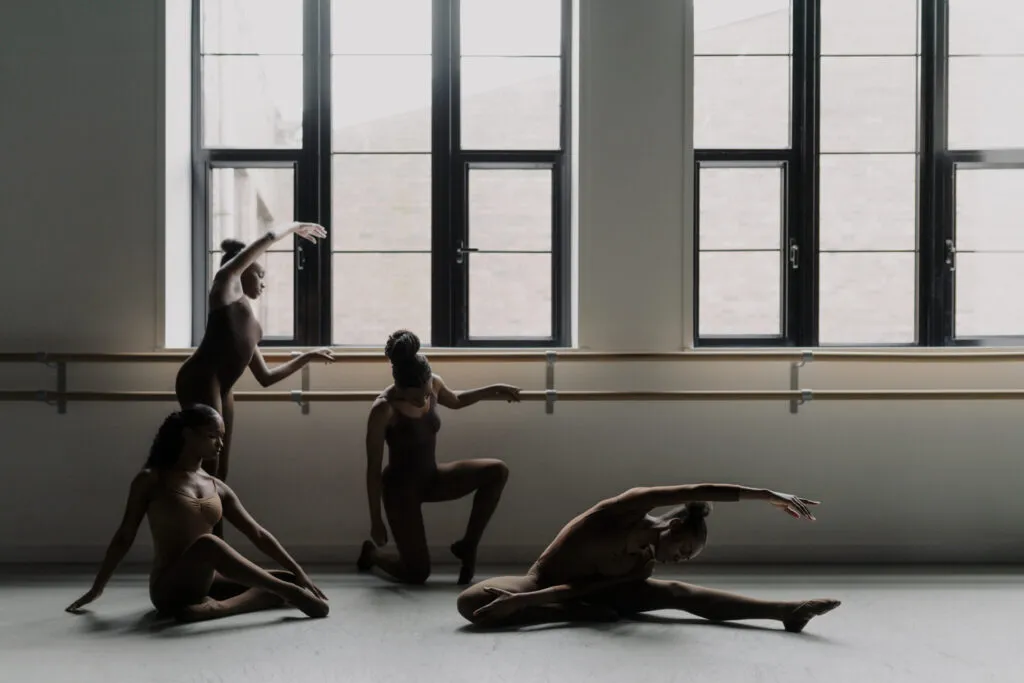 Multiple dancers photographed in the dance studio stretching before class