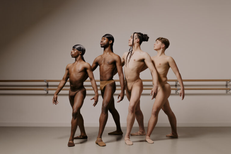 picture shows four adult male dancers posing in a line, left to right from darkest skin tone to lightest.